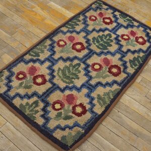 A hooked rug featuring a repeating pattern of stylized red and pink flowers and green leaves set against a beige background with a blue zigzag border, all by Rugs On Net. by Rugs On Net