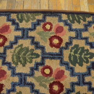 Close-up of a hooked rug featuring stylized red and pink flowers with green leaves against a beige background, framed by a blue geometric border. This is a Rugs On Net design. by Rugs On Net