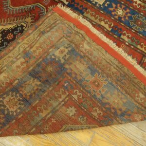 Close-up view of the folded edge of an antique rug showing the worn back and vibrant front patterns by Rugs On Net. by Rugs On Net