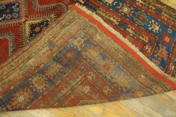 Close-up view of the folded edge of an antique rug showing the worn back and vibrant front patterns by rugs on net. By rugs on net
