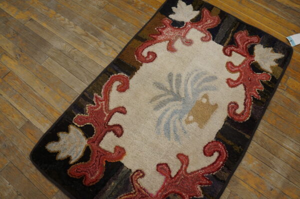 A close-up of a colorful hooked rug with a central cream area and red scrollwork border, by rugs on net. By rugs on net