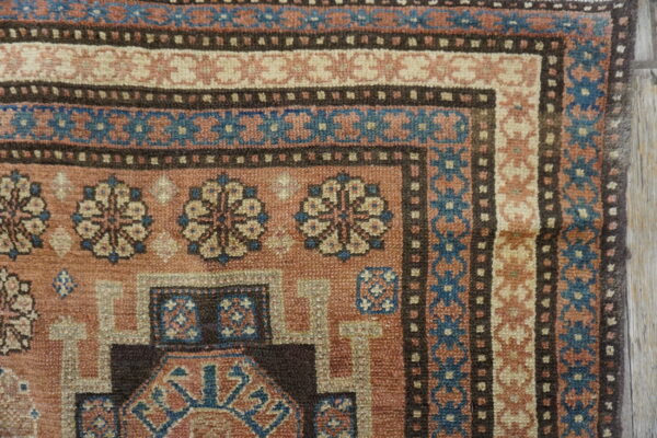 Close-up of the corner design of the tribal rug, featuring terracotta, blue, and cream geometric patterns by rugs on net