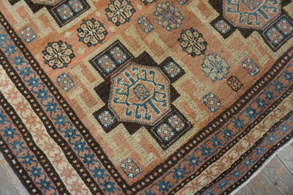 Close-up of a vintage rug featuring geometric motifs in salmon, beige, and blue tones by rugs on net. By rugs on net
