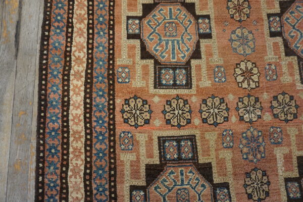 Close-up of a geometric patterned rug with earthy tones and blue accents by rugs on net. By rugs on net