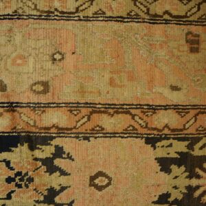 Close-up of a vintage rug with faded pink and tan geometric patterns and dark accents, by Rugs On Net