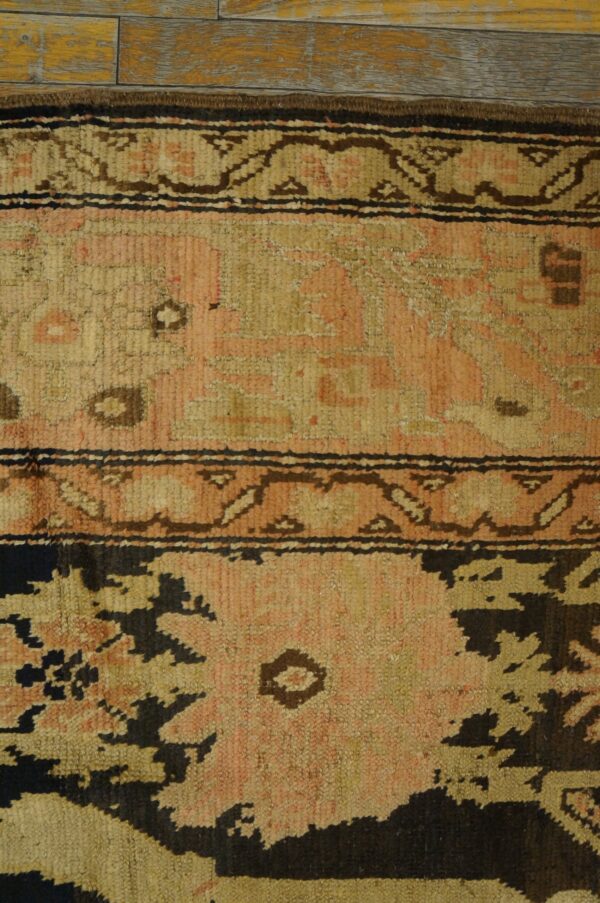 Close-up of a vintage rug with faded pink and tan geometric patterns and dark accents, by rugs on net
