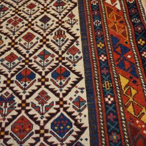 Close-up of the field and border of a geometric rug featuring diamond motifs on a cream ground, by Rugs On Net