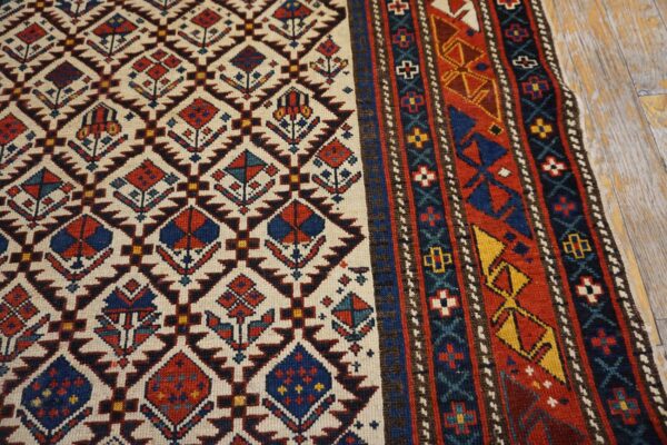 Close-up of the field and border of a geometric rug featuring diamond motifs on a cream ground, by rugs on net