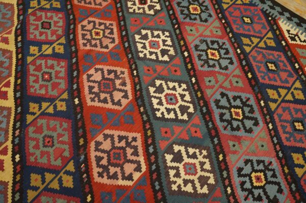 Close-up of a vibrant, geometric kilim rug pattern featuring alternating vertical stripes of medallions in red, blue, and teal backgrounds, by rugs on net