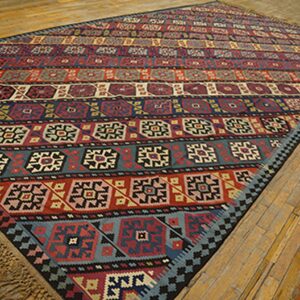 Colorful striped kilim rug with geometric patterns laid on a wooden floor by Rugs On Net