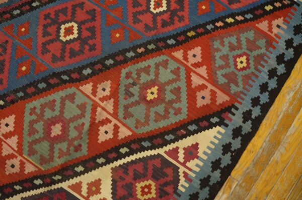 Close-up of a colorful kilim rug with geometric patterns in red, blue, and teal by rugs on net. By rugs on net