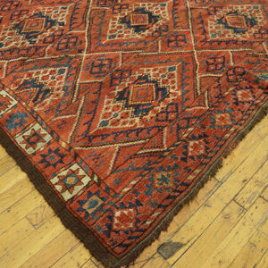Close-up corner of a red and blue geometric rug on a wooden floor by Rugs On Net