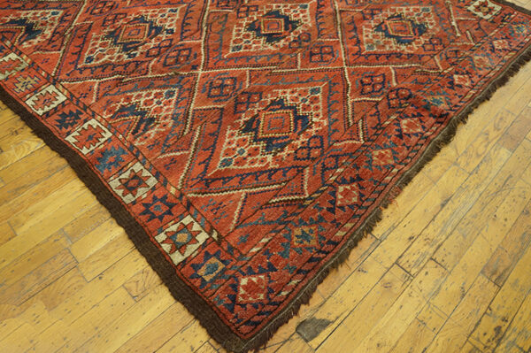 Close-up corner of a red and blue geometric rug on a wooden floor by rugs on net