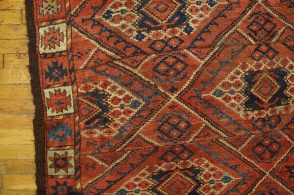 Close-up of a richly textured, antique rug with geometric patterns in red, blue, and cream, by rugs on net. By rugs on net