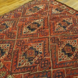 Close-up of a richly patterned, antique red and navy rug on a wooden floor by Rugs On Net. by Rugs On Net