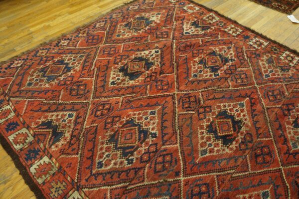 Close-up of a richly patterned, antique red and navy rug on a wooden floor by rugs on net. By rugs on net