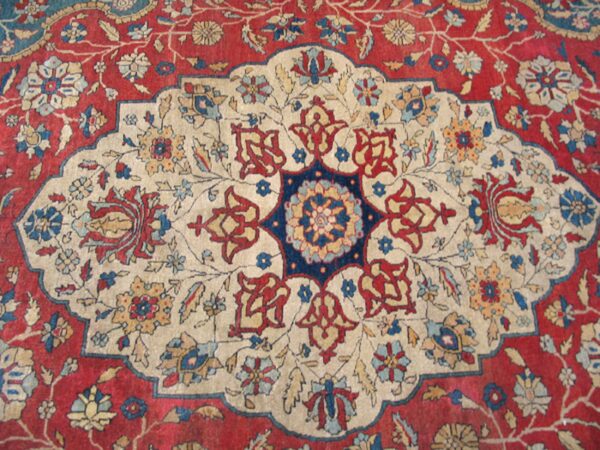 Close-up of a traditional persian rug design featuring a cream medallion on a red field by rugs on net. By rugs on net