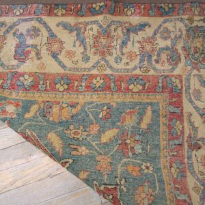 Close-up corner detail of an antique rug with faded floral patterns in beige, blue, and red by Rugs On Net. by Rugs On Net