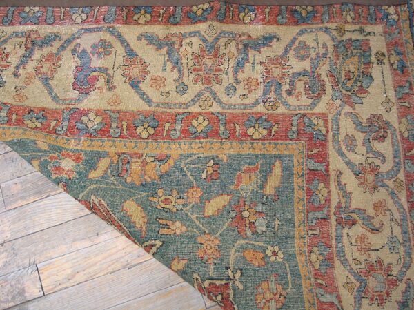 Close-up corner detail of an antique rug with faded floral patterns in beige, blue, and red by rugs on net. By rugs on net