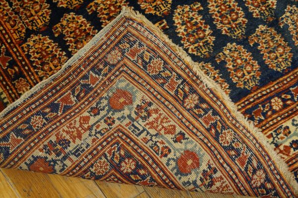 Close-up showing the backing and fringe of a dark blue and rust patterned rug by rugs on net. By rugs on net