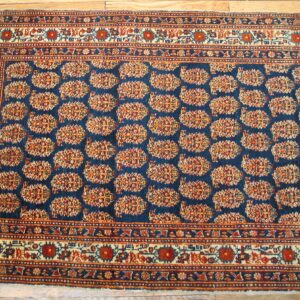 Close-up of a deep blue rug with repeating geometric medallions in red and gold, by Rugs On Net