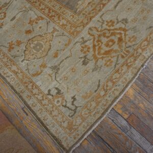 Close-up of a light green and orange patterned rug corner on wood floors by Rugs On Net