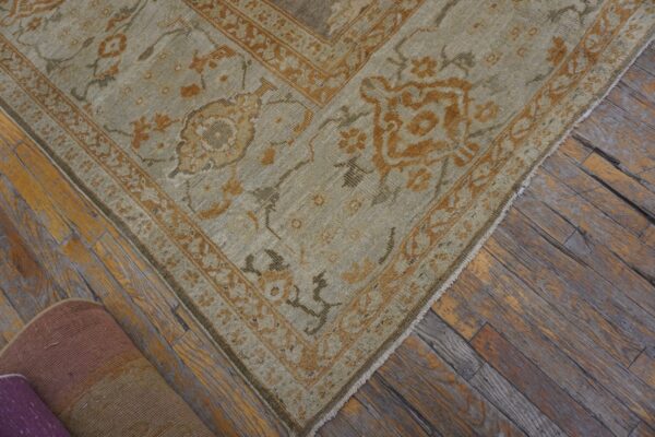 Close-up of a light green and orange patterned rug corner on wood floors by rugs on net