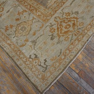 Close-up of a muted beige and rust-toned traditional rug corner on aged wood floors by Rugs On Net