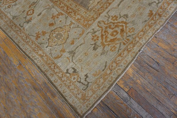 Close-up of a muted beige and rust-toned traditional rug corner on aged wood floors by rugs on net