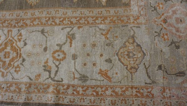 Close-up of a light field rug with faded orange and grey floral motifs and a geometric border by rugs on net