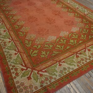 Close-up of an antique rug featuring a salmon field with faded floral motifs and a detailed border in shades of green and beige, by Rugs On Net