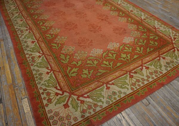 Close-up of an antique rug featuring a salmon field with faded floral motifs and a detailed border in shades of green and beige, by rugs on net