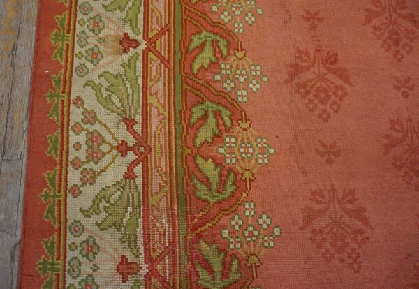 Close-up of the border detail on a salmon-colored rug featuring green and white floral motifs by rugs on net. By rugs on net