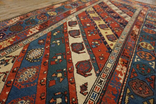 Close-up of a colorful striped rug with geometric motifs in red, blue, and cream, by rugs on net
