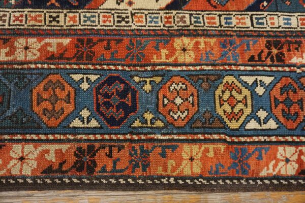 Close-up of geometric patterns in rust, blue, and cream on an antique rug by rugs on net