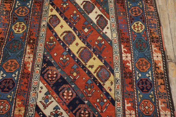 Close-up of a richly colored rug with diagonal stripes and geometric motifs in red, blue, and cream, by rugs on net