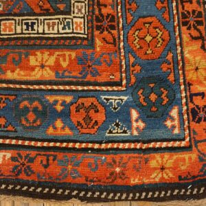 Close-up of the border detail on an antique rug, showing rich orange, blue, and black geometric patterns by Rugs On Net. by Rugs On Net