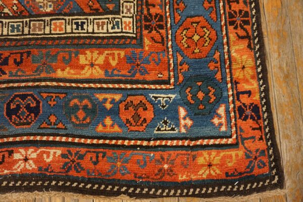 Close-up of the border detail on an antique rug, showing rich orange, blue, and black geometric patterns by rugs on net. By rugs on net
