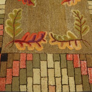 Close-up of a hooked rug featuring autumn leaves and a brick border pattern, by Rugs On Net