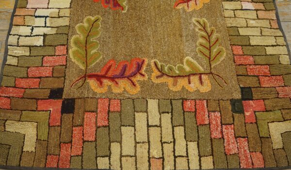 Close-up of a hooked rug featuring autumn leaves and a brick border pattern, by rugs on net
