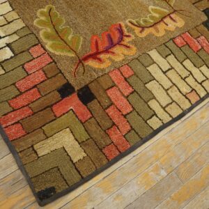 Close-up of a hooked rug featuring autumn leaves and a brick-like border in earth tones by Rugs On Net. by Rugs On Net