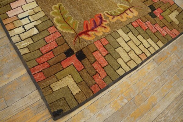 Close-up of a hooked rug featuring autumn leaves and a brick-like border in earth tones by rugs on net. By rugs on net