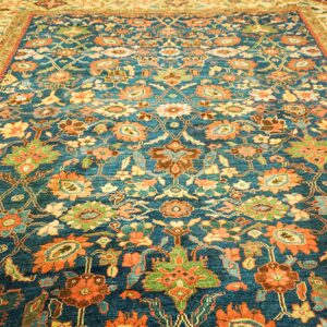 Close-up of a richly patterned blue rug with orange and green floral motifs by Rugs On Net