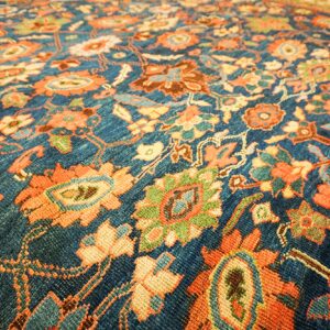 Close-up of a deep blue field with vibrant orange and green floral motifs on the Persian Rug by Rugs On Net. by Rugs On Net