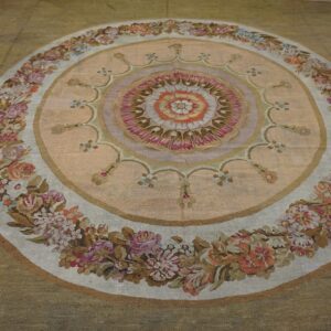 Close-up of a round tapestry rug featuring a central medallion with pink and orange tones, surrounded by a floral garland border, by Rugs On Net. by Rugs On Net
