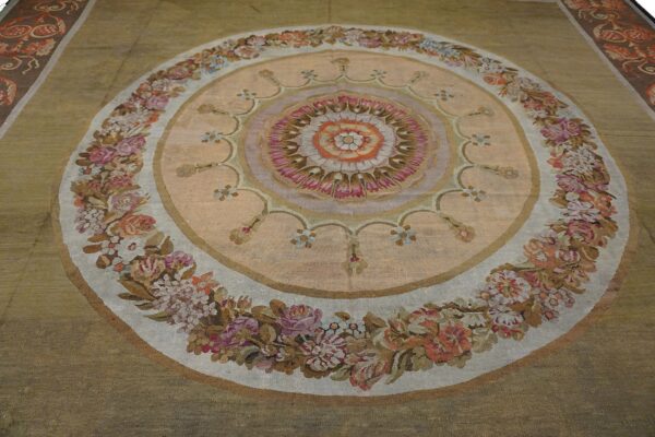 Close-up of a round tapestry rug featuring a central medallion with pink and orange tones, surrounded by a floral garland border, by rugs on net. By rugs on net