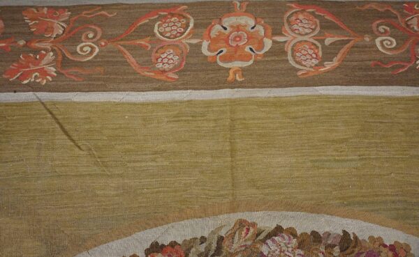 Close-up of a tapestry border featuring orange floral motifs on brown, next to a solid olive field, by rugs on net
