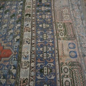 Close-up of a vintage rug with blue, pink, and earthy tones featuring geometric patterns by Rugs On Net. by Rugs On Net