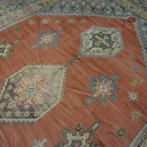 Close-up of a terracotta field rug with scattered geometric motifs and a detailed border, by Rugs On Net