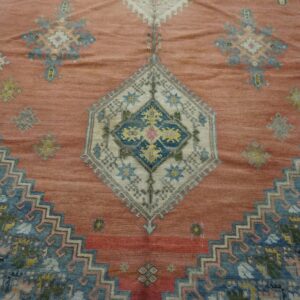 Close-up of a salmon-colored rug with geometric blue and white medallions, by Rugs On Net